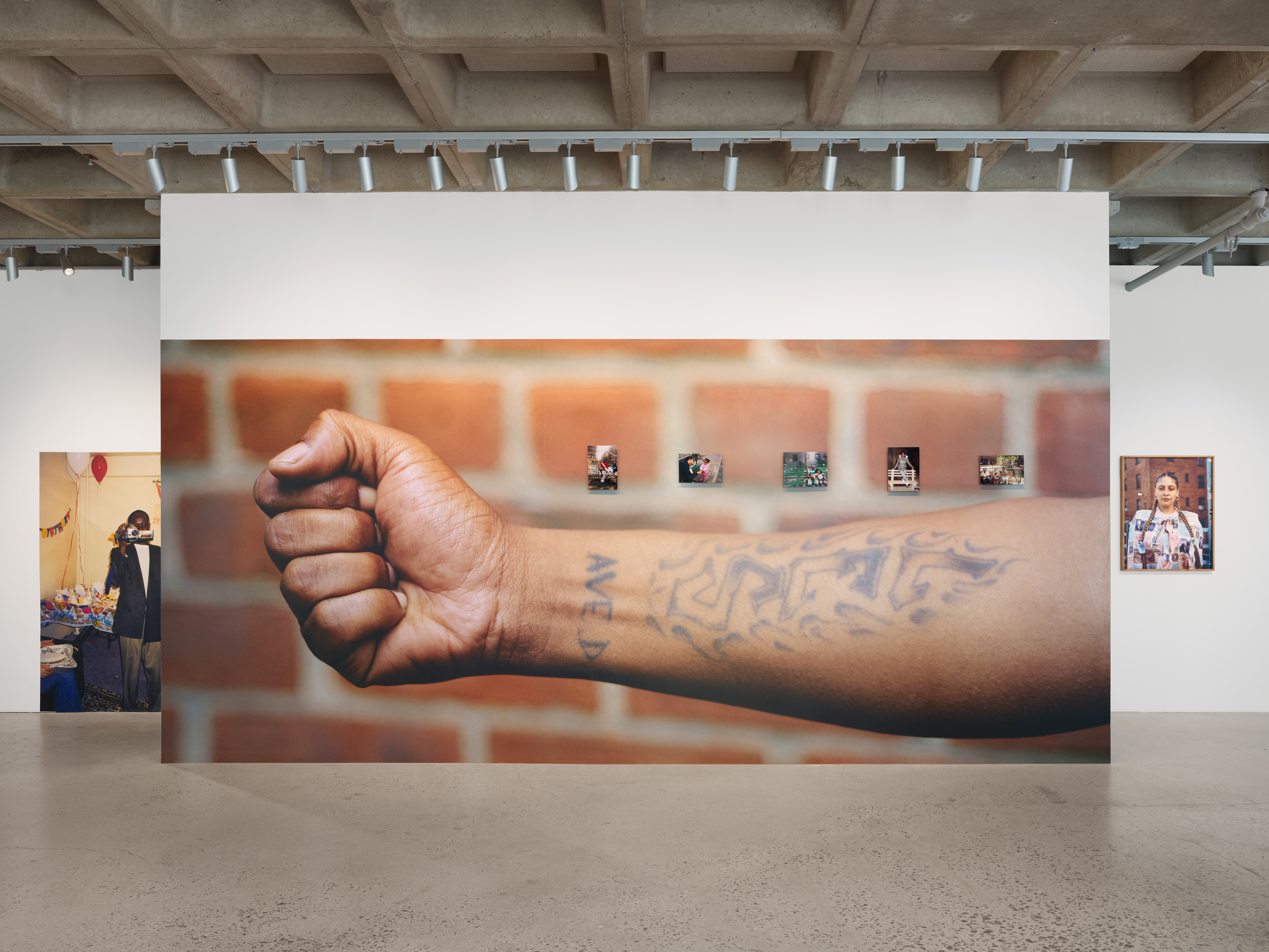 gallery image with large scale photo of forearm with a tattoo that says LES Ave D. another large scale photo of a man holding a camcorder.