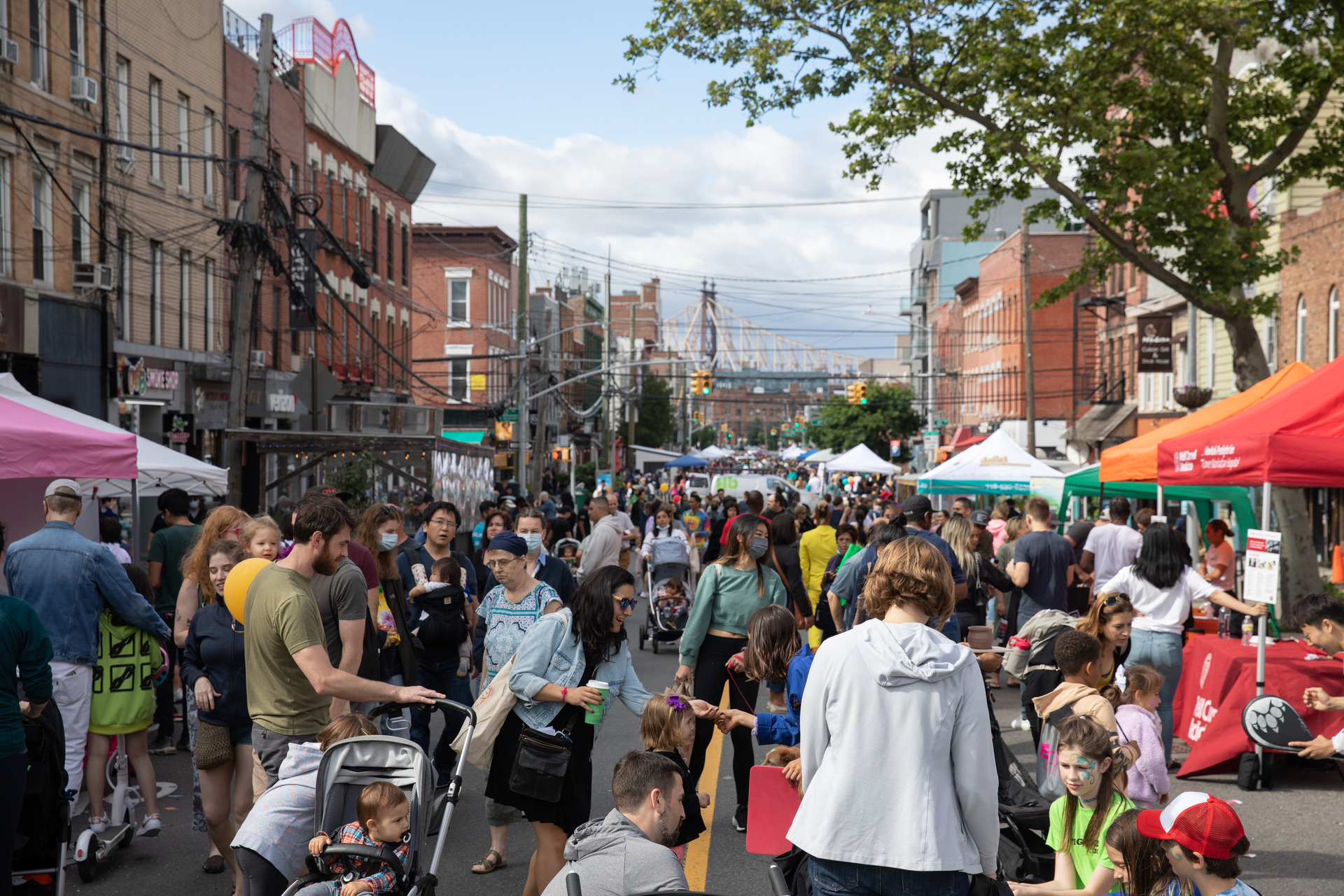 Vernon Boulevard lined with colorful tents and a crowd of families with children.