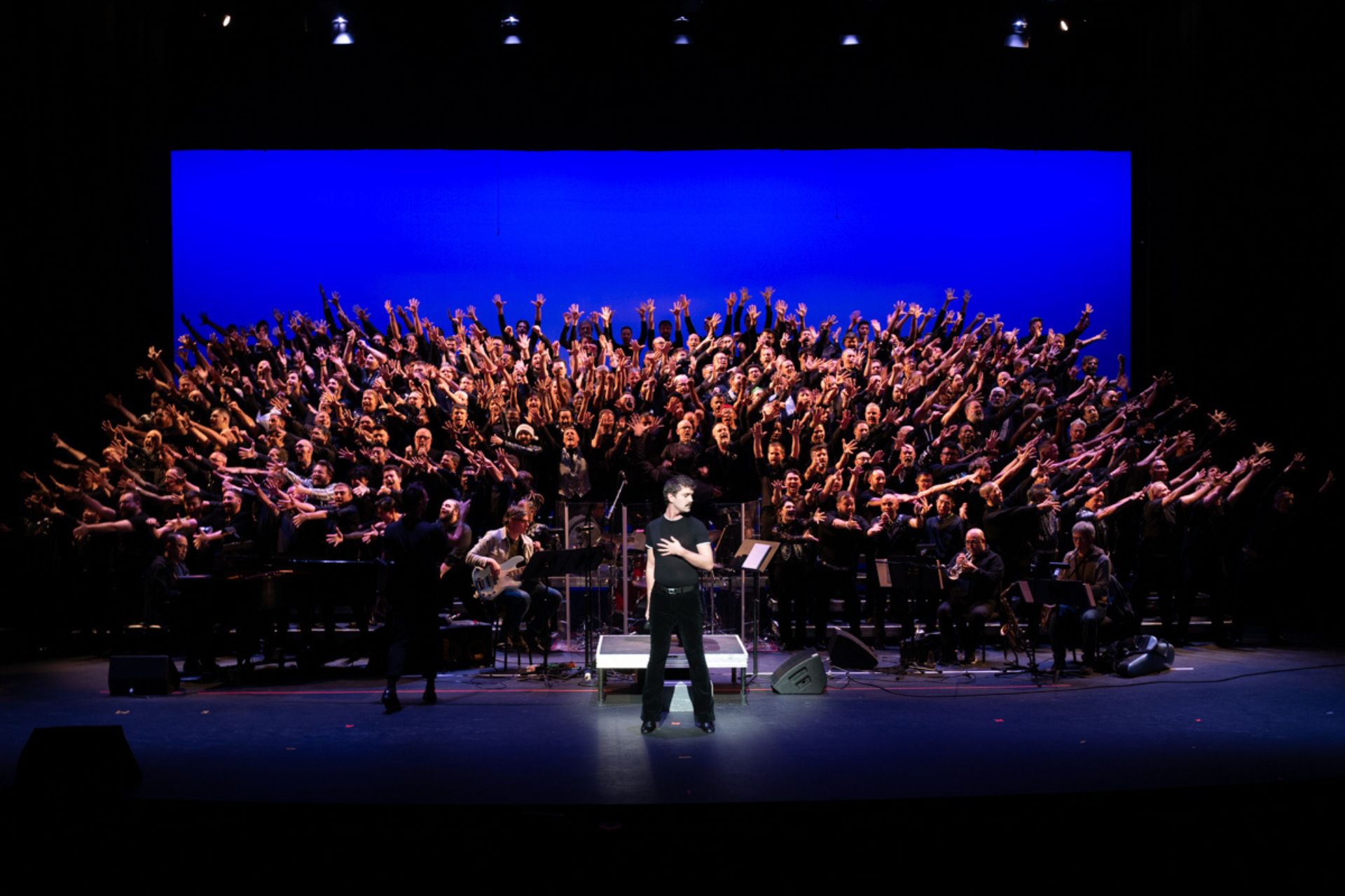 The New York City Gay Men's Chorus posing in joy behind a disco soloist